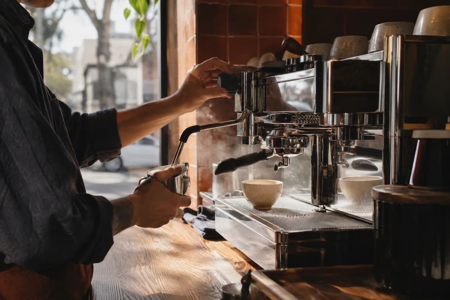 An Ember barista pouring milk into a coffee in a warm and welcoming café